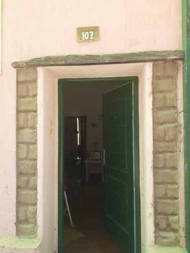 a green door in a room with a brick wall at Casa Chica in Cafayate