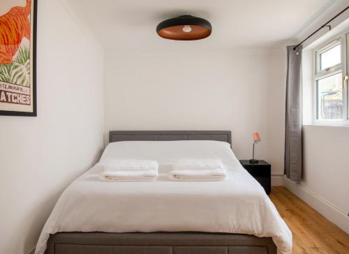 a bedroom with a bed with white sheets and a window at -NEWLY REFURBISHED- Stylish Apartment 5 minutes from Station w Garden in Brighton & Hove