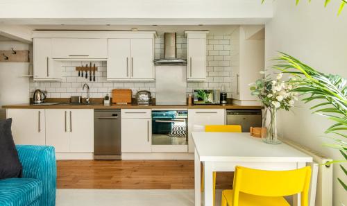 uma cozinha com armários brancos e cadeiras amarelas em -NEWLY REFURBISHED- Stylish Apartment 5 minutes from Station w Garden em Brighton & Hove