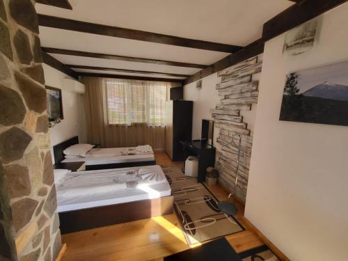 a room with two beds and a stone wall at Oasis Guest House in Dobrinishte