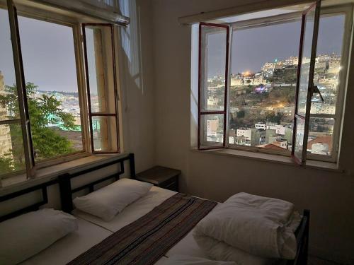 a bedroom with two beds and two windows at Rainbow House in Amman