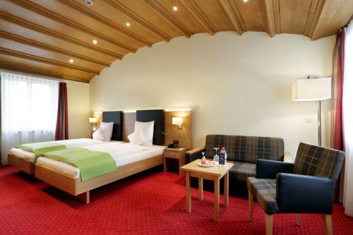a hotel room with a bed and two chairs at Best Western Plus Hotel Bahnhof in Schaffhausen