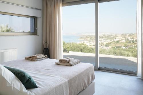 een slaapkamer met een bed en een groot raam bij AGAVE HILL LUXURY HOUSE in Chania