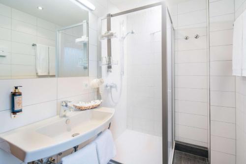 a white bathroom with a sink and a shower at Best Western Blankenburg Hotel in Coburg