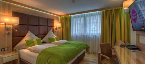 um quarto com uma cama com lençóis verdes e uma televisão em Best Western Plus Hotel Füssen em Füssen