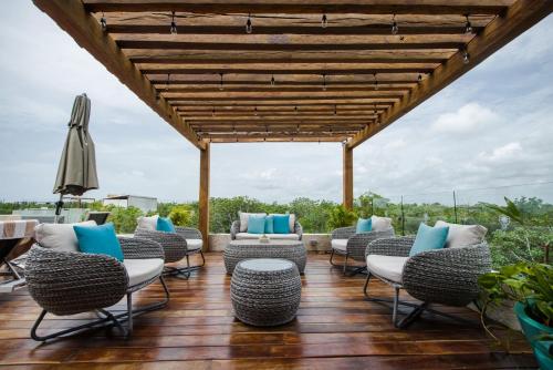 a patio with chairs and an umbrella on a wooden floor at Naay Tulum Curamoria Collection in Tulum