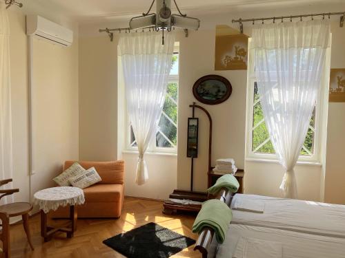 a bedroom with a bed and a couch and two windows at Apartman Villa Amelia in Mošćenička Draga