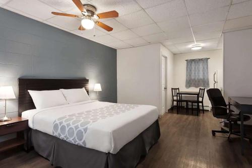 a bedroom with a bed with a ceiling fan and a desk at Howard Johnson by Wyndham Grande Prairie in Grande Prairie