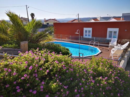 a backyard with a swimming pool and flowers at Family Surf Home - Bungalow 5 in Ribamar