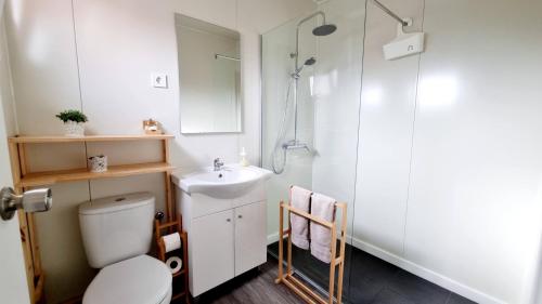 La salle de bains est pourvue de toilettes, d'un lavabo et d'une douche. dans l'établissement Family Surf Home - Bungalow 5 - Aulas de Surf, piscina e bicicleta, à Ribamar
