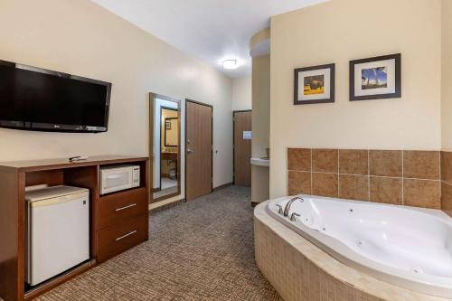 Comfort Inn & Suites Greenville I-70 في Greenville: حمام كبير مع حوض استحمام وتلفزيون بشاشة مسطحة