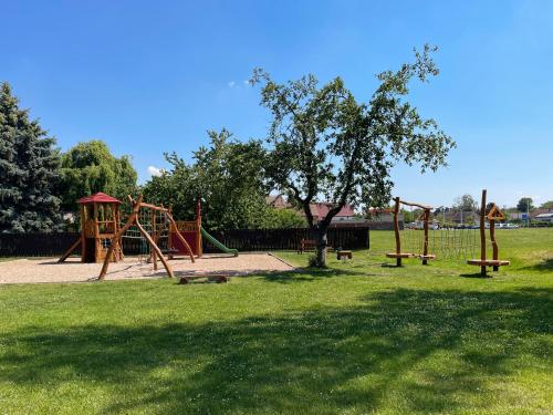 a park with a playground with a tree and benches at apartmán NA NOC V BOHDANČI in Lázně Bohdaneč