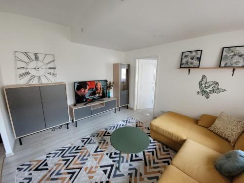 a living room with a couch and a clock on the wall at Lovely Apartment Near City Center (w/ Parking) in Cluj-Napoca