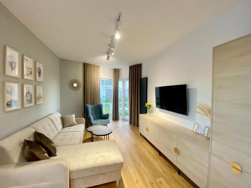ein Wohnzimmer mit einem weißen Sofa und einem Fernseher in der Unterkunft Apartament MORZA SZUM Gąski in Gąski