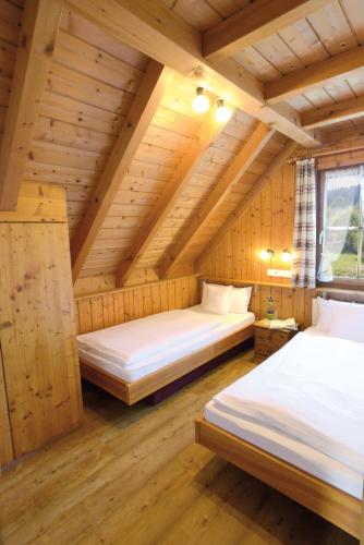 two beds in a room with wooden ceilings at Landhaus Anja in Freudenstadt