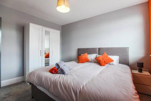 a bedroom with a large bed with orange pillows at PRIME LOCATION - Modern Central Apartment in Bristol