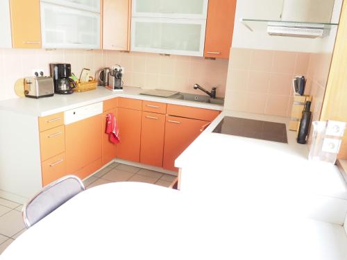 une petite cuisine avec des armoires orange et un évier dans l'établissement La suite de l'Observatoire, à Strasbourg