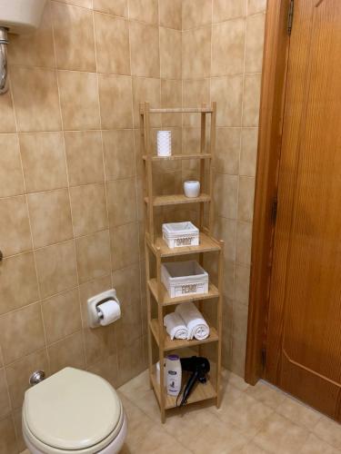 a bathroom with a toilet and a shelf with towels at La Villetta al Mare in Porto Cesareo
