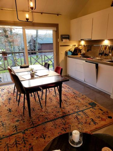 a kitchen with a dining table and a kitchen with a view at Chalet au bois d'Ourthe in Somme-Leuze