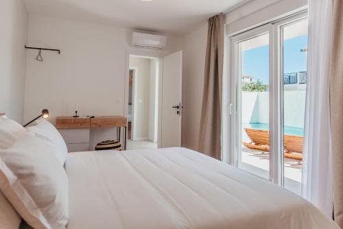 a white bedroom with a bed and a balcony at High View House in Okrug Donji