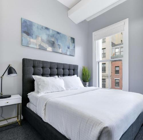 a white bedroom with a large bed and a window at Temple Place 6th Floor in Boston