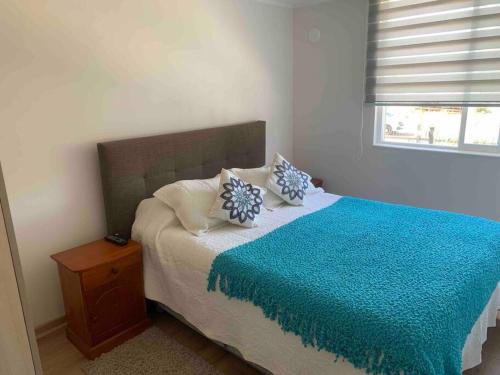 Un dormitorio con una cama con una manta azul. en Depto full equipado con estacionamiento y piscina, en Temuco