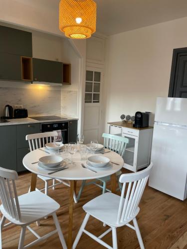 Il comprend une cuisine équipée d'une table blanche avec des chaises et d'un réfrigérateur blanc. dans l'établissement Duplex rénové quartier plage, à Mers-les-Bains