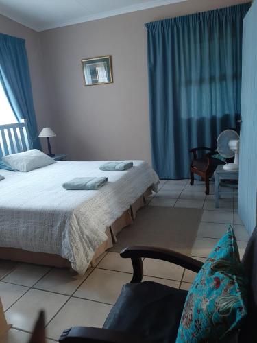 a bedroom with a large bed and a chair at Denmark Farm Stay in Cradock