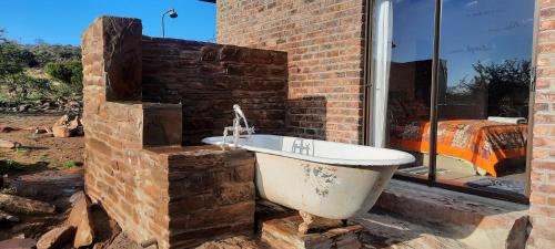 a bath tub sitting next to a brick wall at Denmark Farm Stay in Cradock