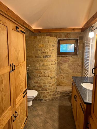 a bathroom with a toilet and a stone wall at Luxury Gloria Garden in Występ