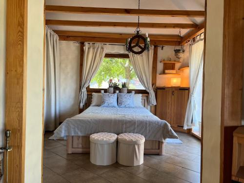 a bedroom with a bed with two white stools at Luxury Gloria Garden in Występ