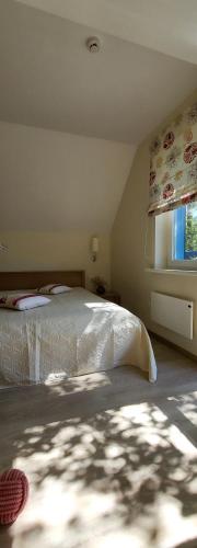 a bedroom with a bed and a window and a bedspread at Pergolt Apartment in Pervalka