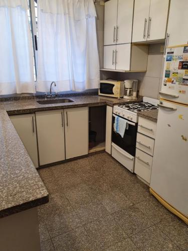 a kitchen with white cabinets and a sink and a stove at verdinegro in Rosario