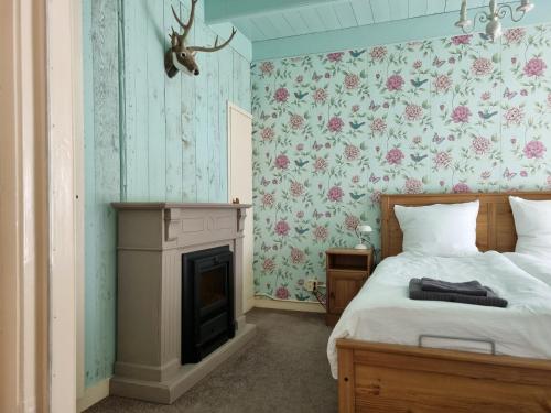 a bedroom with a bed with a fireplace and floral wallpaper at Het Voorhuis boerderij Hoeve Vrede Best in Weesp