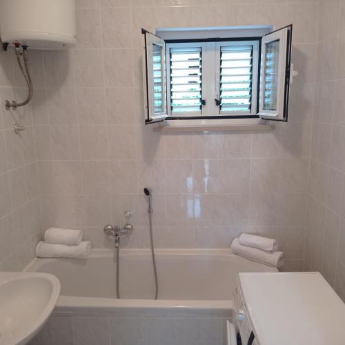 a bathroom with a tub and a sink and a window at My Mediterranean Villa with Huge Garden and own Parking in Lumbarda