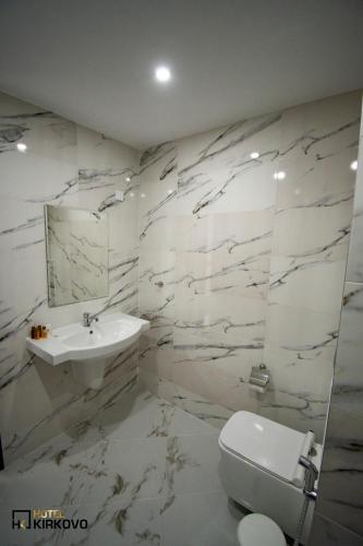 a white bathroom with a sink and a toilet at Hotel Kirkovo in Kirkovo