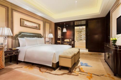 a bedroom with a large bed and a television at Wanda Realm Harbin Hotel in Harbin