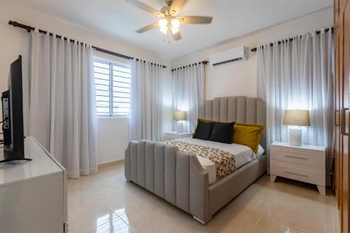 1 dormitorio con cama, sofá y TV en Vista Bella 46 en San Felipe de Puerto Plata