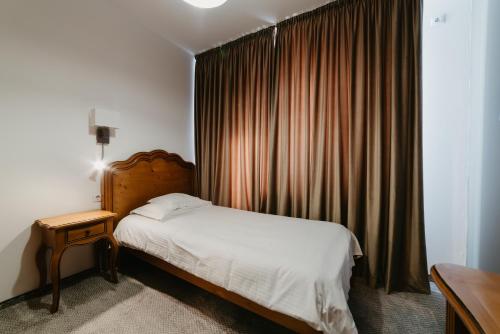 a bedroom with a bed and a window with curtains at Meteor Central in Cluj-Napoca