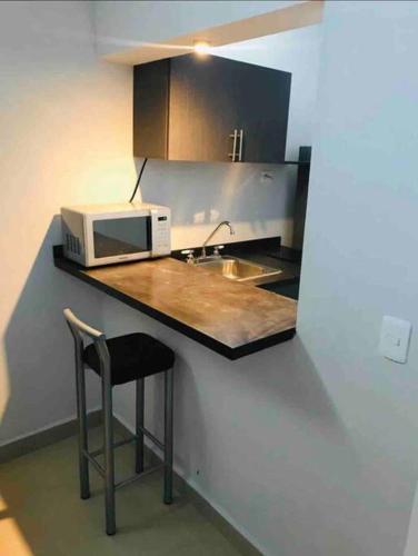 a kitchen with a counter with a microwave and a stool at Departamento hermoso en guadalupe in Monterrey