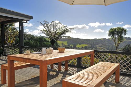 einen Holztisch und Bänke auf einer Terrasse mit Aussicht in der Unterkunft Warwick Hills Rural Bed & Breakfast in Papamoa