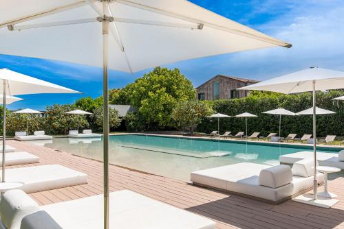 a swimming pool with white umbrellas and lounge chairs at Ramo d'Aria Etna Boutique Hotel in Giarre
