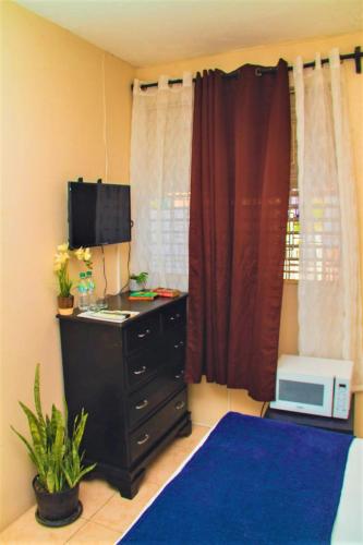 a room with a desk with a microwave and a computer at Eventuality B&B New Kingston in Kingston