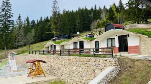 a house on a hill with a stone wall at Resort Valea Tătarilor in Lacu Rosu