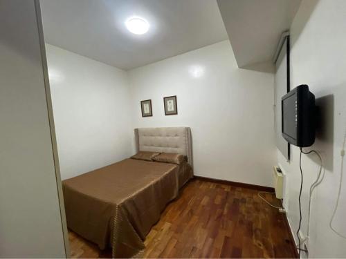 a small bedroom with a bed and a television at Mosaic Tower by LuxuReich in Manila