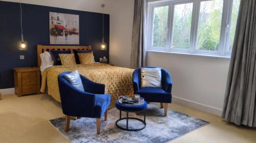 a bedroom with a bed and two blue chairs at Greater London Villa in Chelsfield