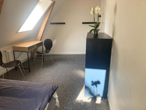 a room with a desk and a table with a vase of flowers at Residens Svalhøj in Hasle