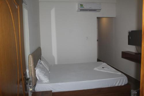 a small bedroom with a white bed in a room at Grace Apart Hotel @Kochi in Cochin