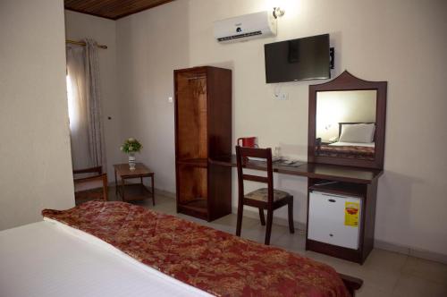 a bedroom with a bed and a desk and a mirror at Lou Ralph Hotel in Accra