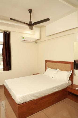a bedroom with a bed with a ceiling fan at Grace Apart Hotel @Kochi in Cochin